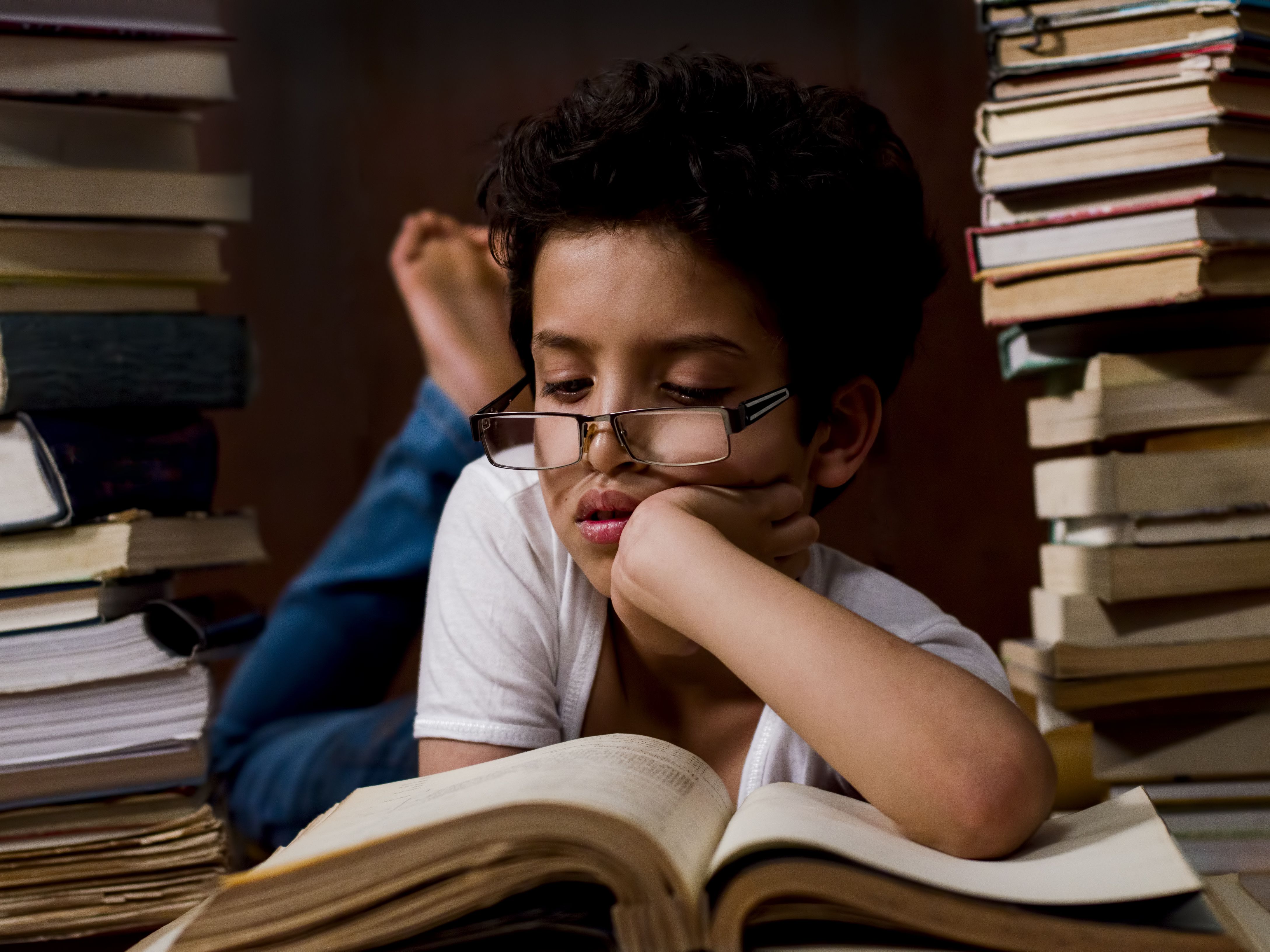 He is reading a book. Чтение. Вдумчивое чтение. Трудности чтения. Ребенок.