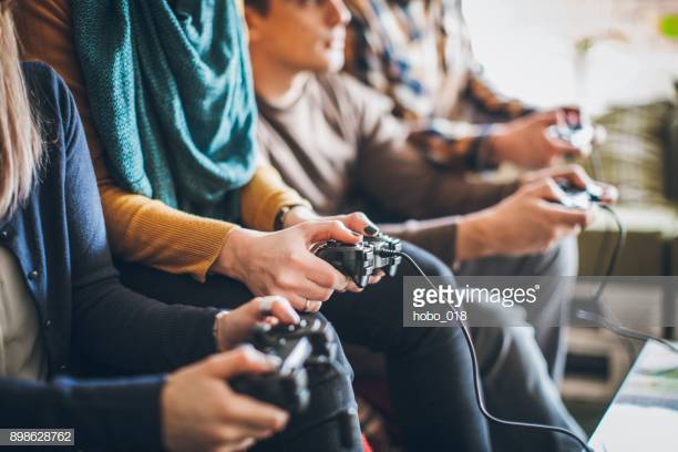 Pessoas alegres se divertindo com jogos de videogame, usando console de tv  e competição de jogos online na televisão. jogando desafio no hangout com  os amigos, bebendo álcool em casa. tiro de tripé.